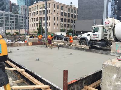 Local finishing crew power-troweling a large poured concrete foundation slab at a commercial job site
